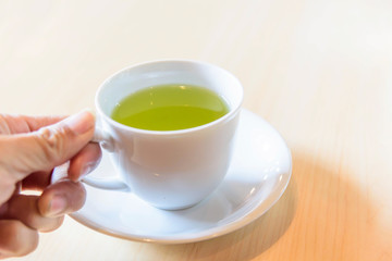 Fototapeta na wymiar The man hold the hot green tea on his hand before drink / hot matcha