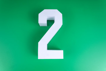 Volumetric close figure of number two laying on green bakground