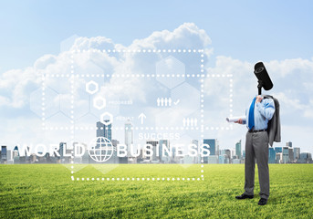 Camera headed man standing on green grass against modern cityscape