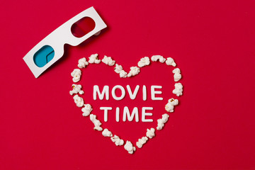 Movie time written in heart shape with 3d glasses on red background