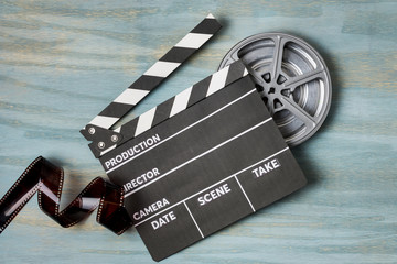 Film stripes with clapperboard and film reel on blue textured background