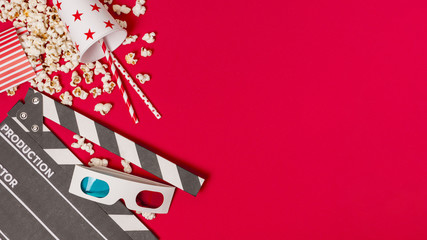 Clapperboard; popcorns and takeaway glass with drinking straws and popcorns on red background