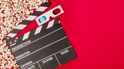 Popcorns with clapperboard and 3d glasses on red backdrop