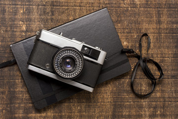 An old-fashioned camera over the closed diary on wooden desk