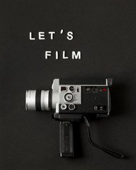 Camcorder camera with text let's film on black background