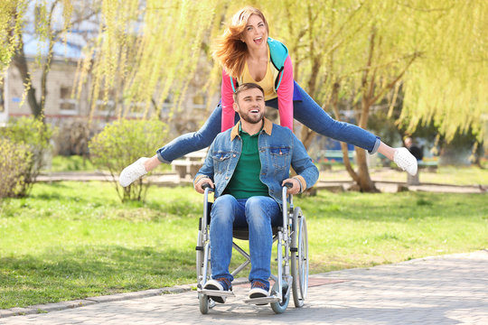 Young man in wheelchair and joyful woman at park