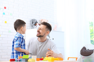 Father and son playing at wooden table in light room