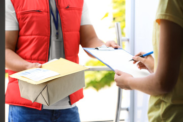 Woman signing for delivered parcels on doorstep, closeup. Courier service