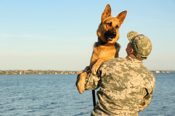 Man in military uniform with German shepherd dog outdoors
