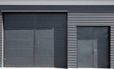 Big and small grey back doors in corrugated metal wall