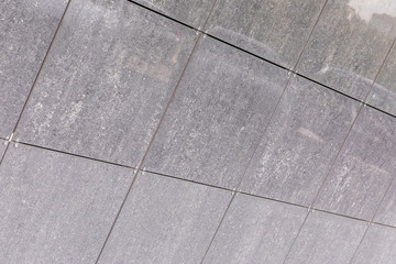 Gray dirty concrete panels on wall surface, diagonal view.