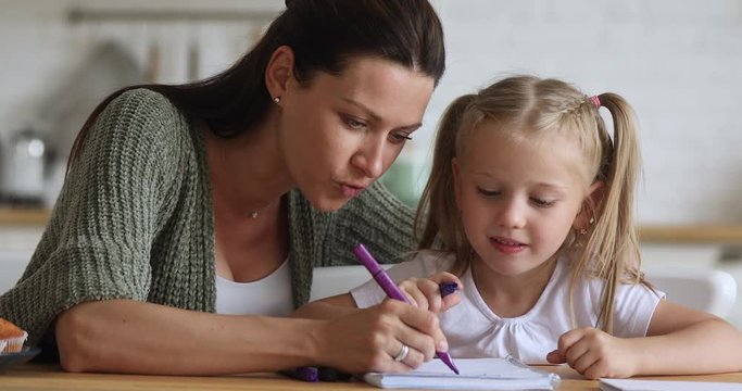 Happy mom teaching kid girl drawing with felt pen together