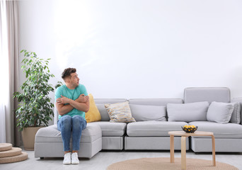 Young man suffering from cold at home. Air conditioner malfunction