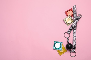 Ball gag and condoms on pink background, top view with space for text. Sex game
