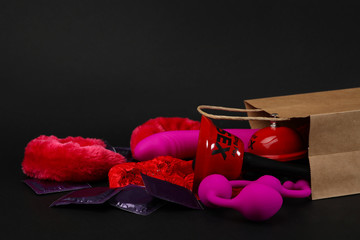 Shopping bag and different sex toys on black background