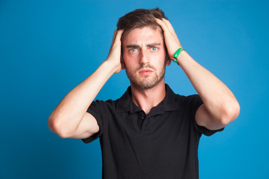 Chico joven sobre fondo azul, expresiones en su cara sobre fondo azul