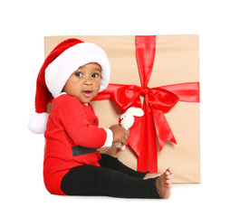 Festively dressed African-American baby with toy near Christmas gift on white background