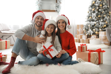 Portrait of happy family with Christmas gifts on floor at home - Powered by Adobe
