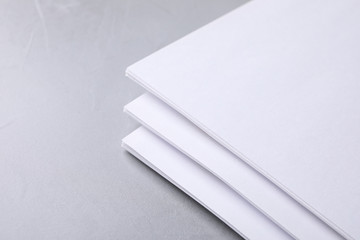 Blank paper sheets on light grey stone background, closeup. Mock up for design