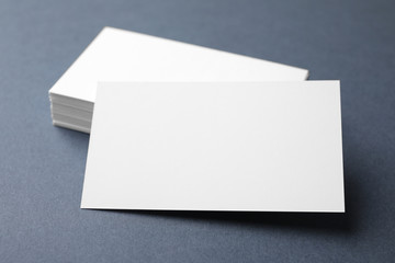 Blank business cards on dark grey background, closeup. Mock up for design