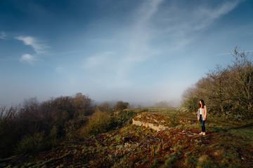 Fototapeta na wymiar une jeune fille se promène vers une falaise. Une femme regardant un paysage brumeux. Une adolescente vers une falaise et du brouilard.