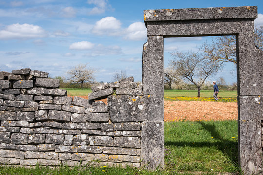 L'entr&eacute;e d'un verger. Un homme dans un jardin. Entr&eacute;e et muret en pierres s&egrave;ches dans un jardin de campagne. H&eacute;ritage historique. Porte en pierre dans un jardin. Verger de fruitiers.