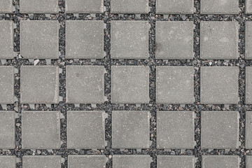 Close-up of dark grey square paving slab with gravel in gaps