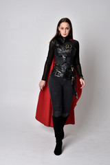 full length portrait of a pretty brunette woman wearing black leather fantasy costume with long red...