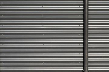 Corrugated metal wall with black tube on the left