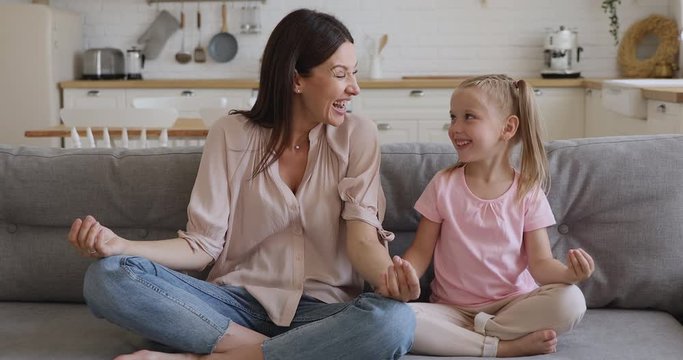 Healthy happy mom teaching kid daughter meditating sit on sofa