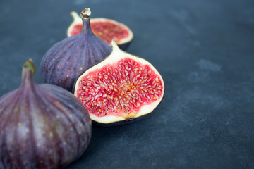 Ripe figs, red slices on dark gray concrete background. Recipe, healthy food concept. Copy space, close-up