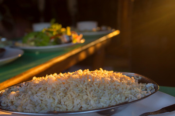 Rice in metal plate on table in asian cafe with sunset light. Recipe, food concept. Close-up, copy space
