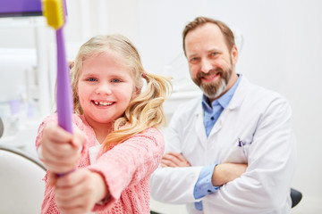 Mädchen und Kinderzahnarzt mit einer Zahnbürste
