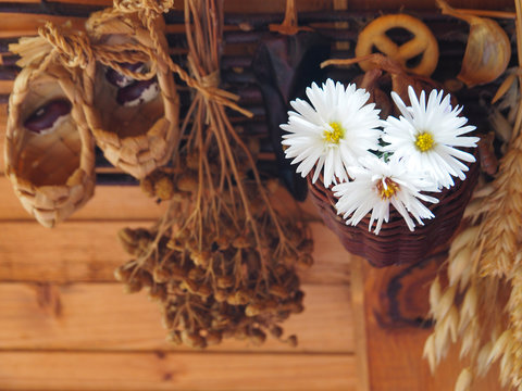 The interior is decorated in a rustic style. On the old wooden wall decorative decoration-a combination of dry plants and fresh flowers, small bast shoes and a hat.