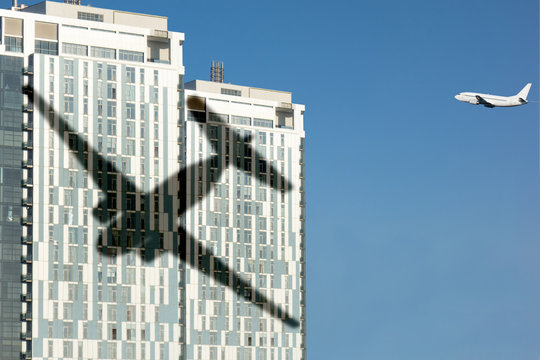 Airplane shadow on skyscraper building. Concept of aviation safety or airport close living. Noise reduction in modern urban lifestyle