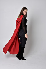 full length portrait of a pretty brunette woman wearing black leather fantasy costume with long red...