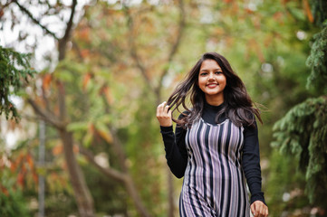 Portrait of young beautiful indian or south asian teenage girl in dress posed at autumn park in...