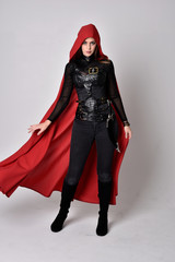 full length portrait of a pretty brunette woman wearing black leather fantasy costume with long red...