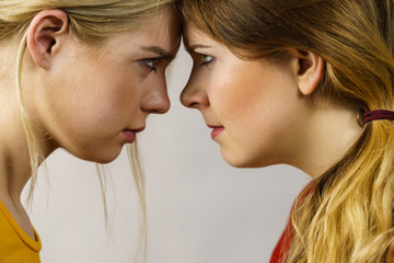 Two girls looking serious at each other.