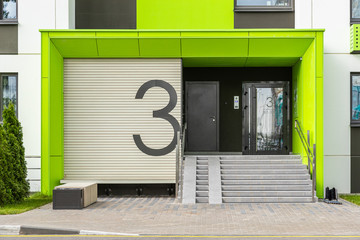 Access to house building number three with glass door, entrance ramp and entryphone