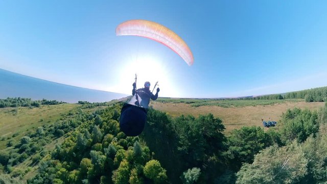 Front view of a person flying with a ram-air parachute. Man Paragliding, beautiful nature background.