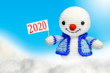 snowman with a sign with the inscription 2020, on a blue background in a snow frame	