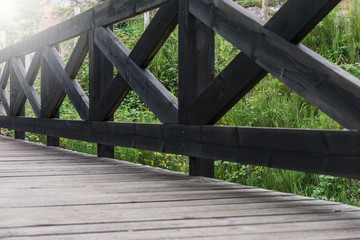 Fototapeta na wymiar dark wooden bridge over river in a mountain forest