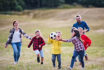 Group of school children with teacher on field trip in nature, playing with a ball.