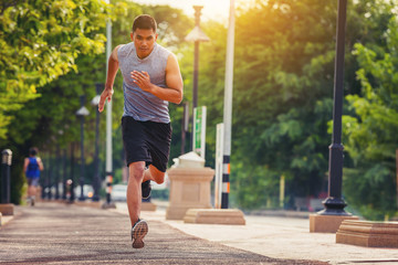 Man running sprinting on road. Fit male fitness runner during outdoor workout with sunset background