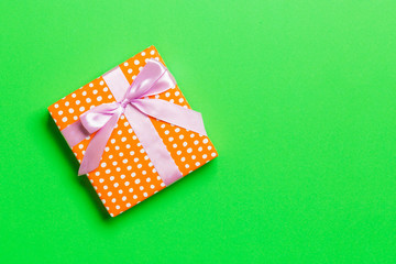 wrapped Christmas or other holiday handmade present in paper with pink ribbon on green background....