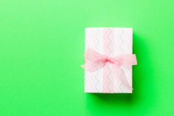 wrapped Christmas or other holiday handmade present in paper with pink ribbon on green background....
