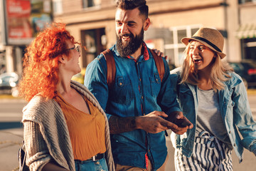 Group of tourists enjoying on vacation, young friends having fun walking on city street during sunset.