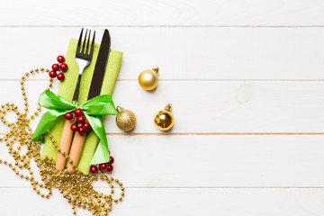 Top view of holiday set of fork and knife on wooden background. Christmas decorations and toys with copy space. New Year Eve concept