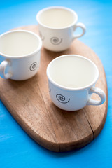 White porcelain cups of coffee, on a wooden platform.